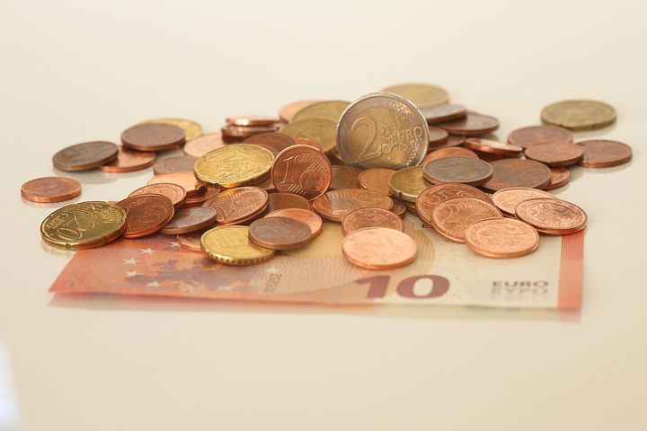 Pile of coins with a ten euro bill