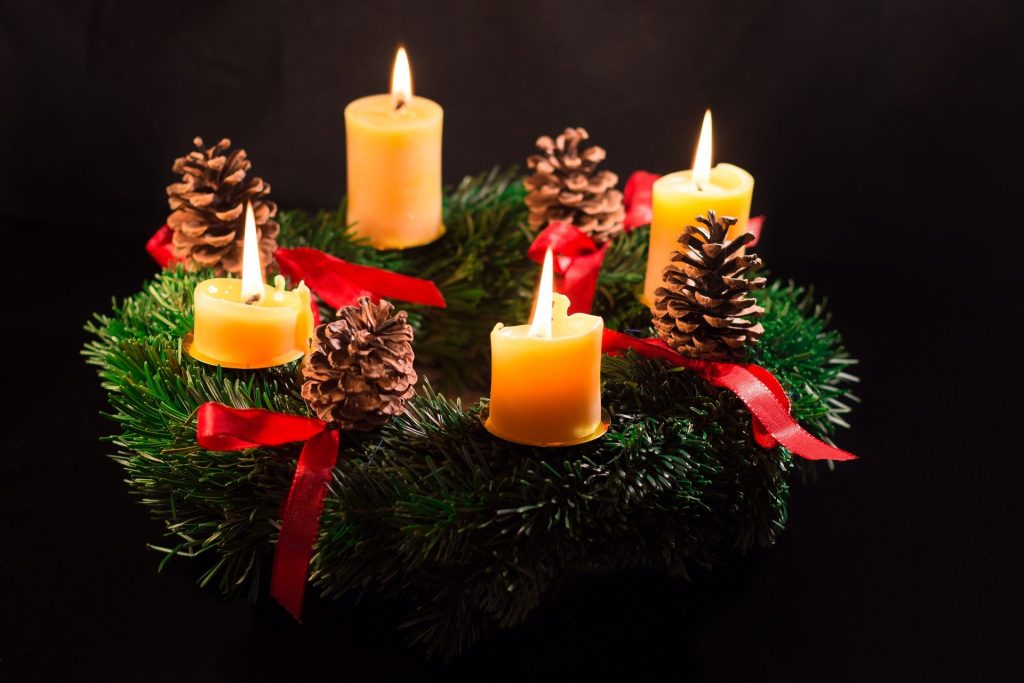 A pine wreath with candles glowing in the dark.