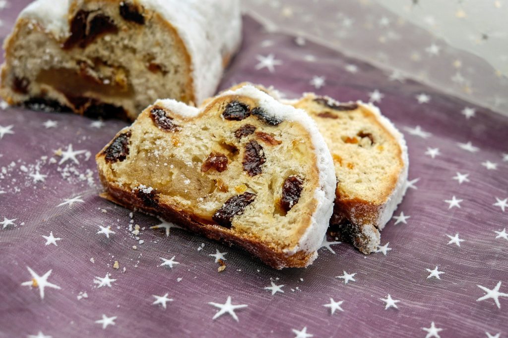 A loaf of traditional German Christmas cake filled with raisins with two slices cut off.