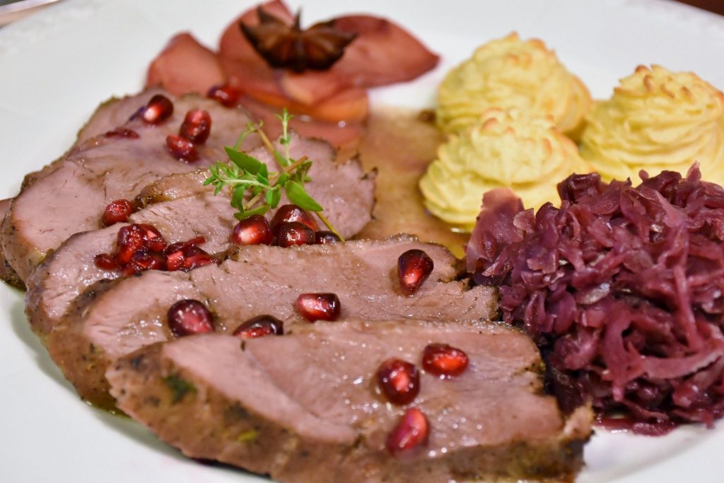 A plate with meat, red cabbage, and mashed potatoes.