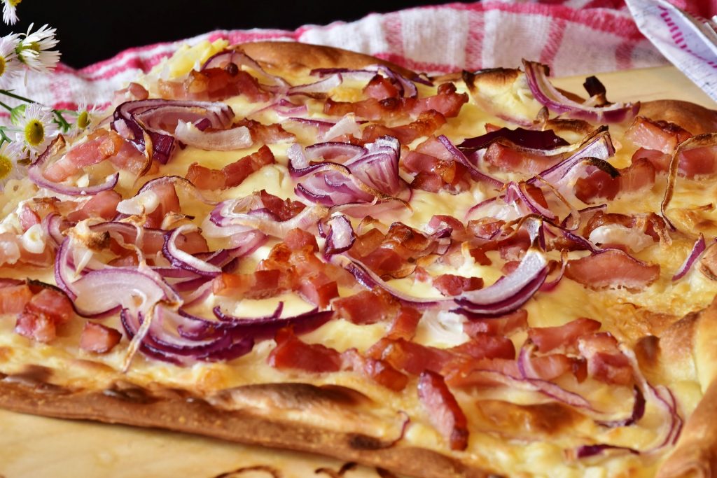 A savory tart topped with red onions and bacon.